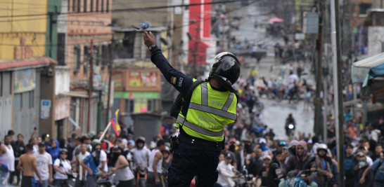 Un policía lanza gases lacrimógenos contra manifestantes.