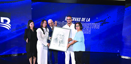 Wilson Rodríguez  director de prensa de Banreservas entrega una placa en que figura el rostro del finado cronista Roosevelt Comarazami a familiares de este.