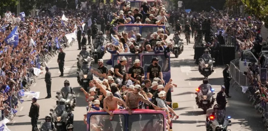 Parte de los jugadores en el desfile de los nuevos monarcas del béisbol y los fanáticos en los extremos.