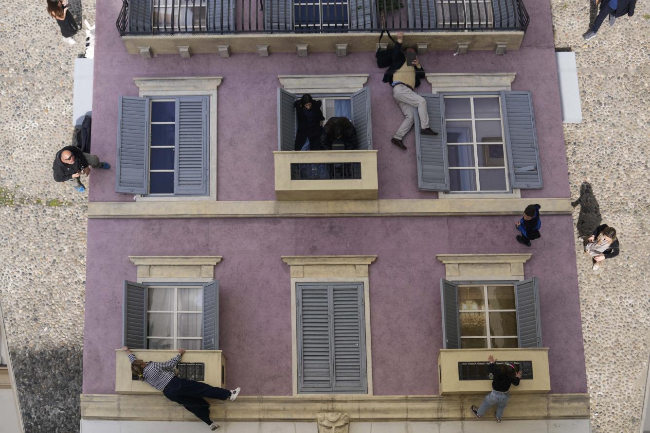 People are reflected in a giant mirror as they take part in the installation by Leandro Erlich at the Palazzo Reale, during the Design Fair exhibition, in Milan.
