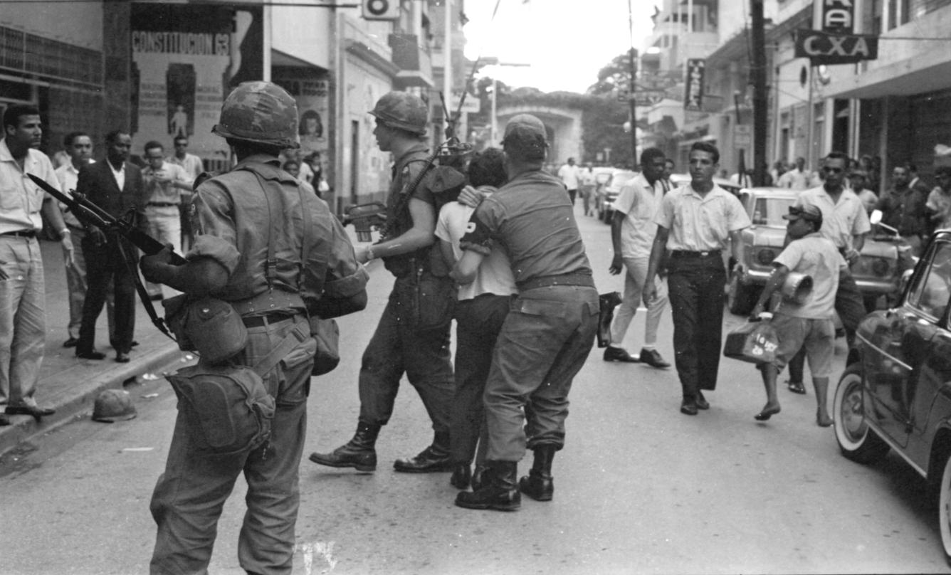 Soldado americano sujeta del cuello a manifestante dominicano en calle de la ciudad colonial durante intervención norteamericana, abril 1965.