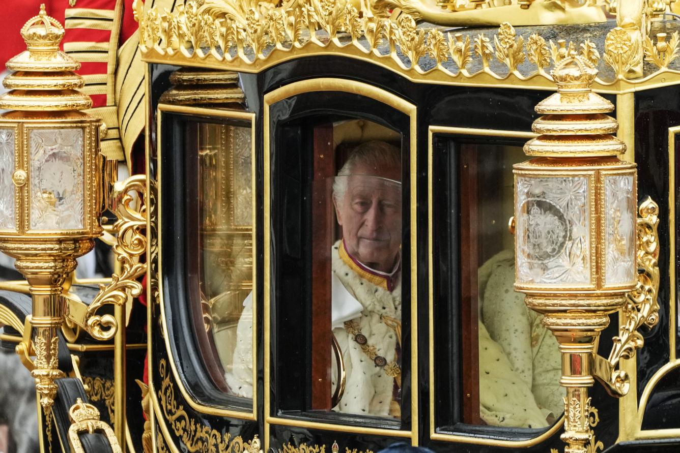 El rey Carlos III de Inglaterra, visto a través de la ventanilla del carruaje Jubileo de Diamante a su salida del Palacio de Buckingham, acompañado por la reina consorte, Camila, para la ceremonia de su coronación, en Londres, el 6 de mayo de 2023.