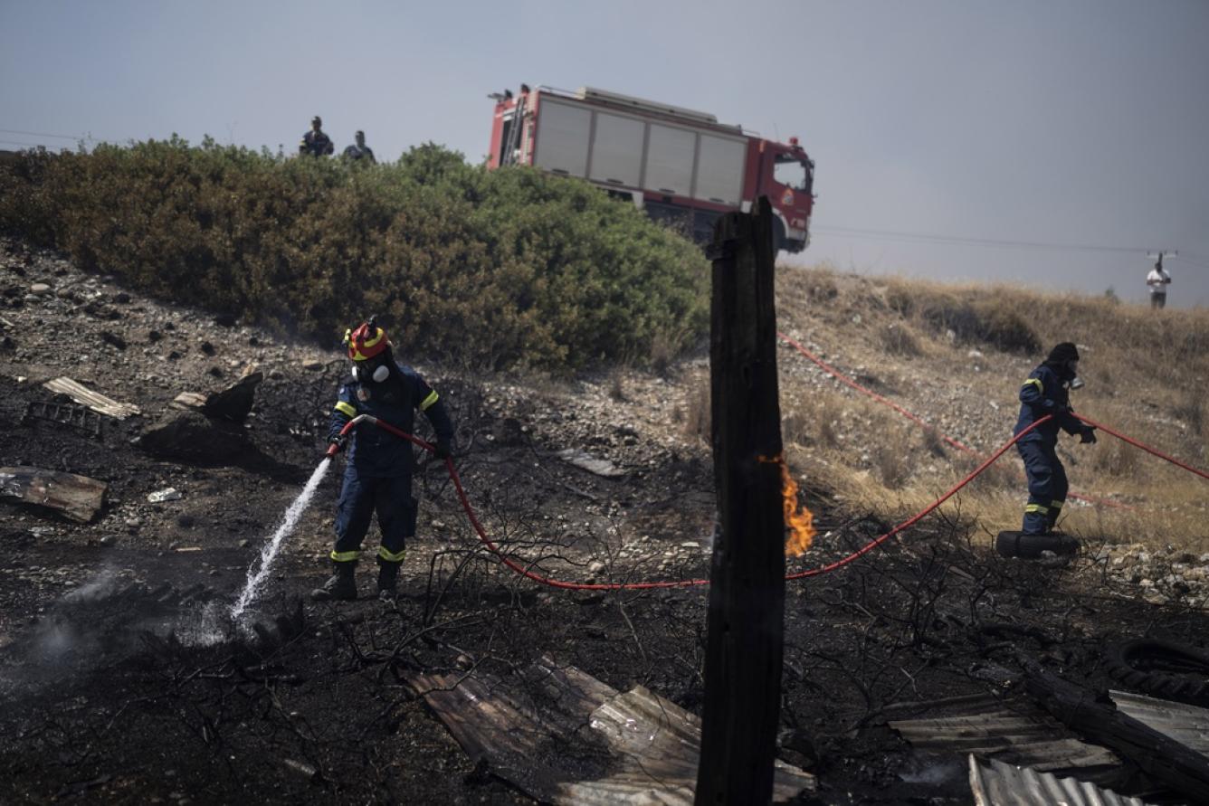 Los bomberos tiran agua en un campo quemado en la aldea de Kiotari, en la isla de Rodas
