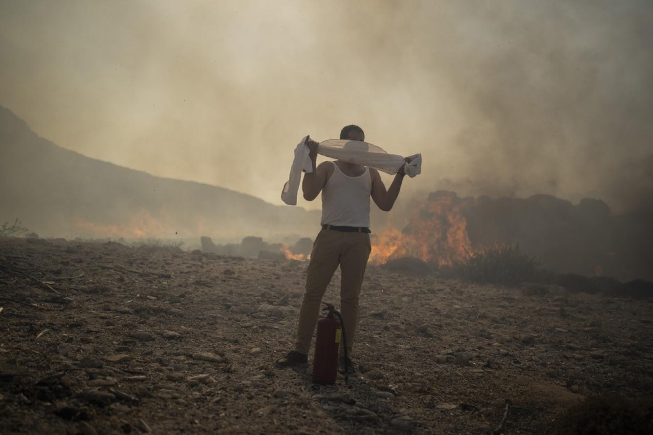 Un residente local intenta extinguir un incendio, cerca del balneario de Lindos, en la isla de Rodas
