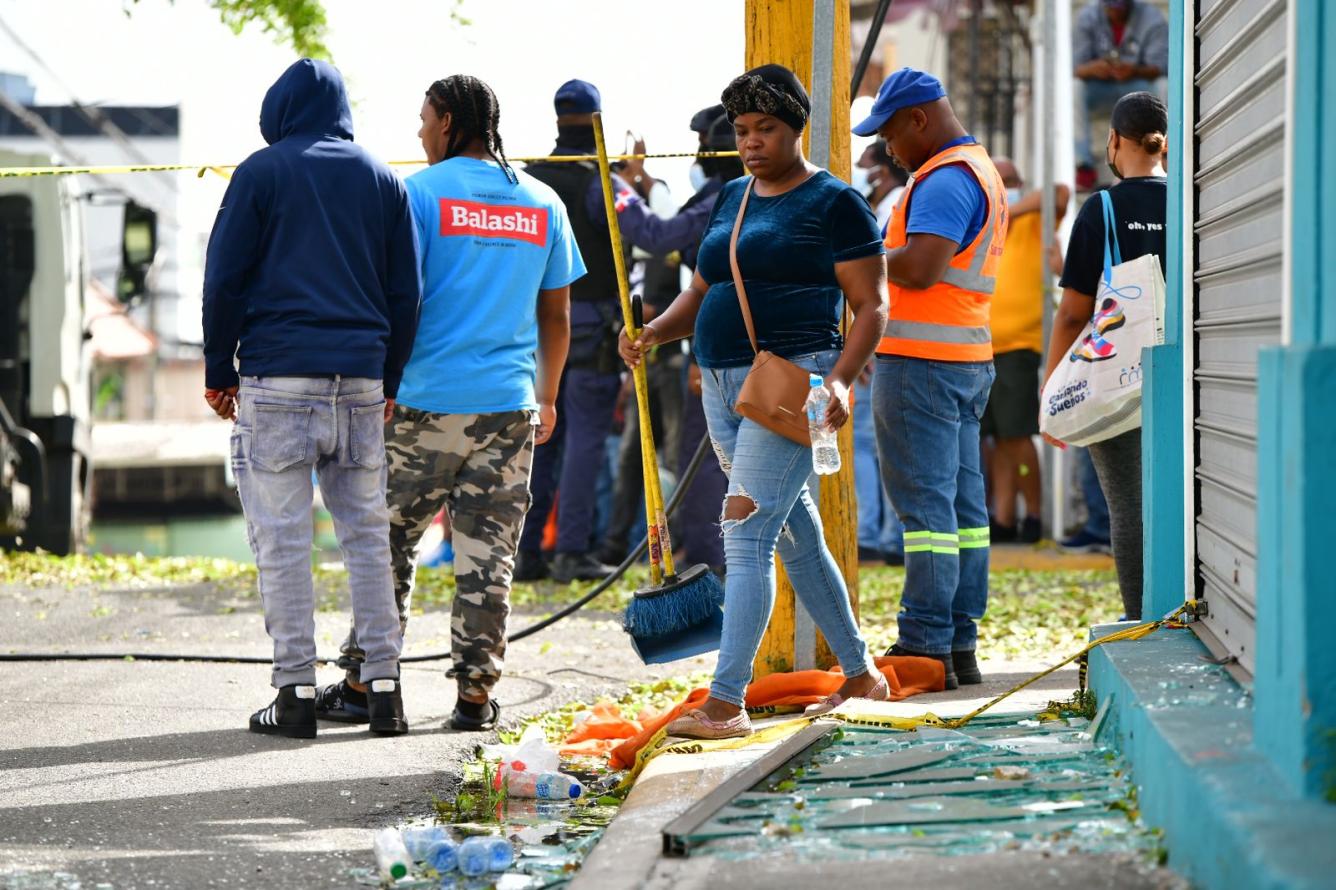 Una mujer limpia una de las calles repleta de vidrios