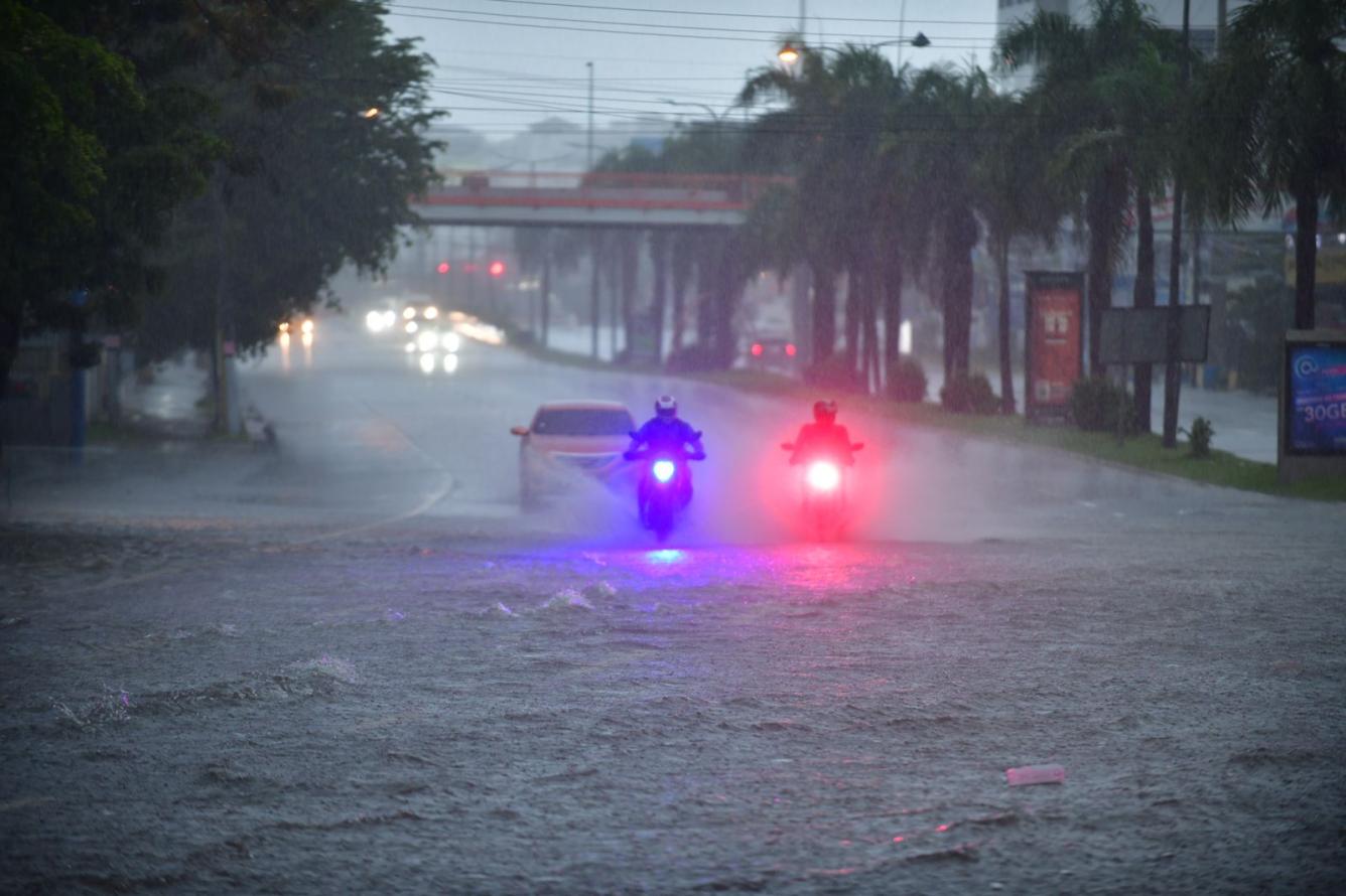 Motoristas circulando por la avenida inundada.