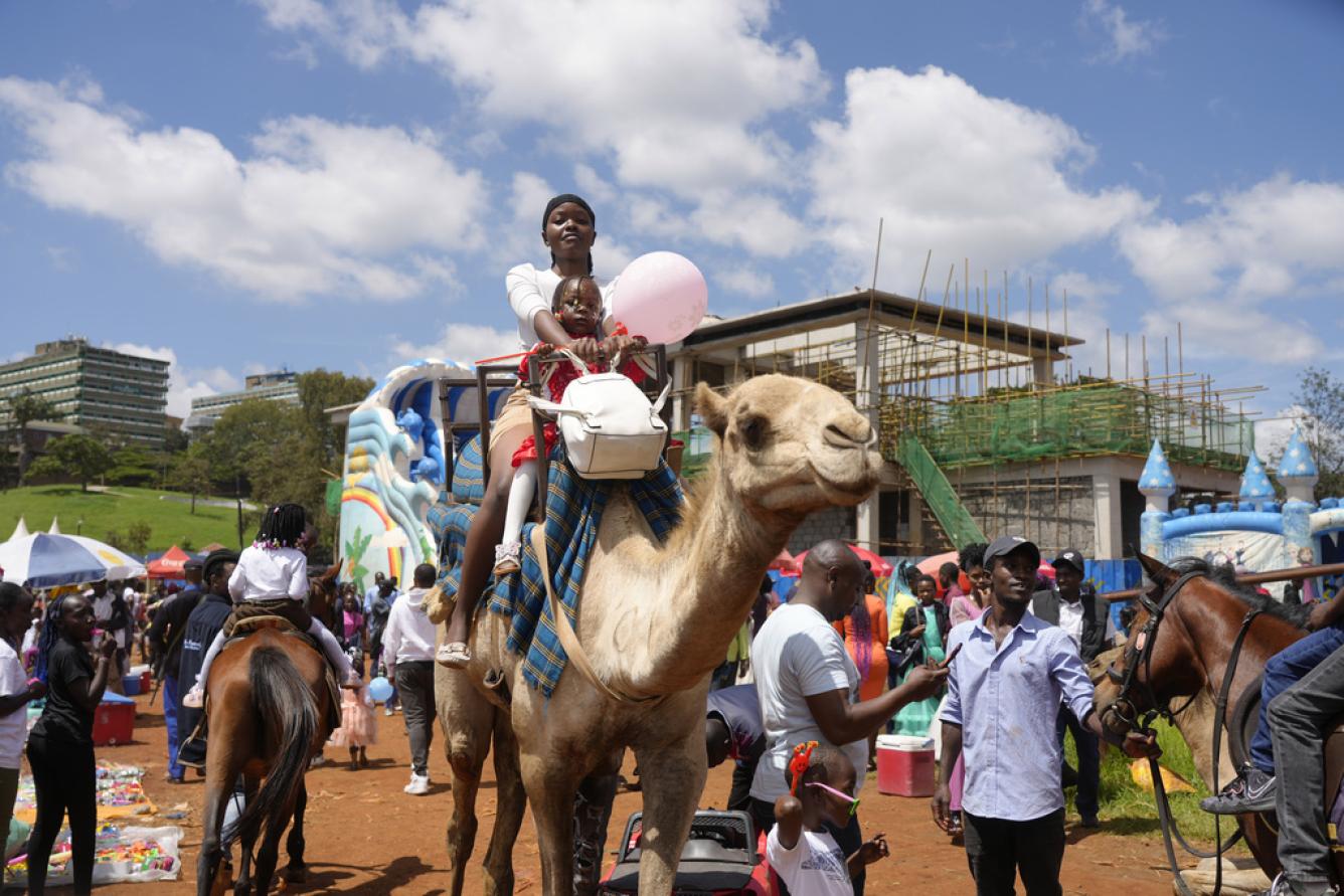 Un keniano disfruta de un paseo en camello en el parque Uhuru, el lunes 25 de diciembre de 2023, durante las vacaciones de Navidad. (Foto AP/Sayyid Azim)