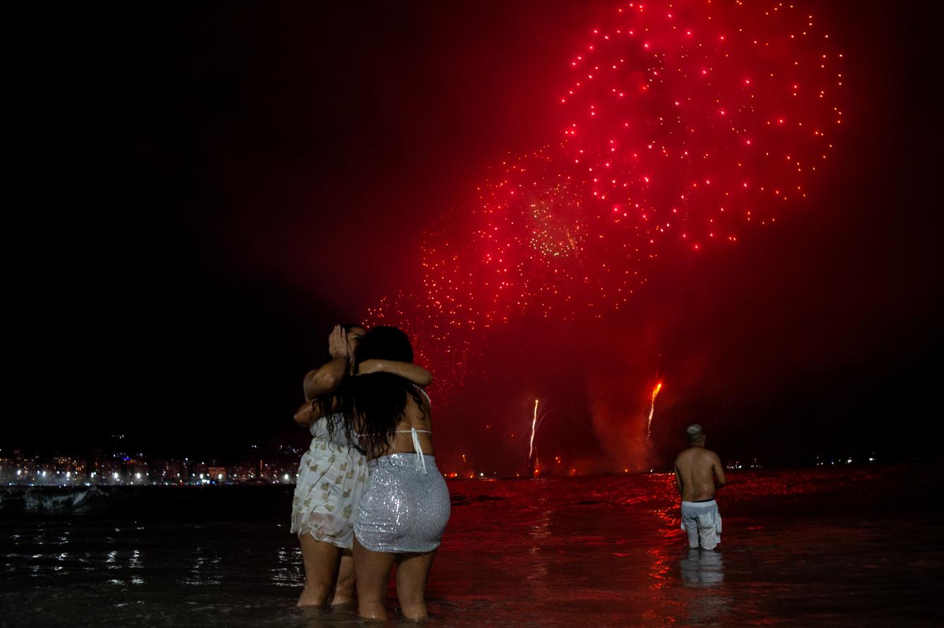 La gente celebra mientras ve los tradicionales fuegos artificiales de Año Nuevo desde el agua de la playa de Copacabana en Río de Janeiro, Brasil, el 1 de enero de 2024.