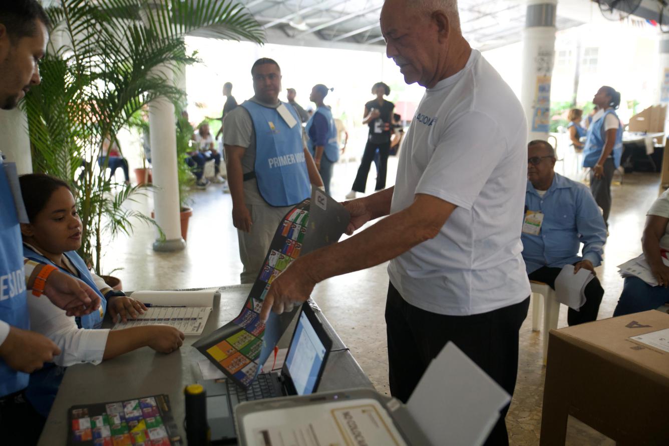 El personal de la Junta Central Electoral encargado de estos comicios municipales le hacen entrega de la boleta electoral a un ciudadano.