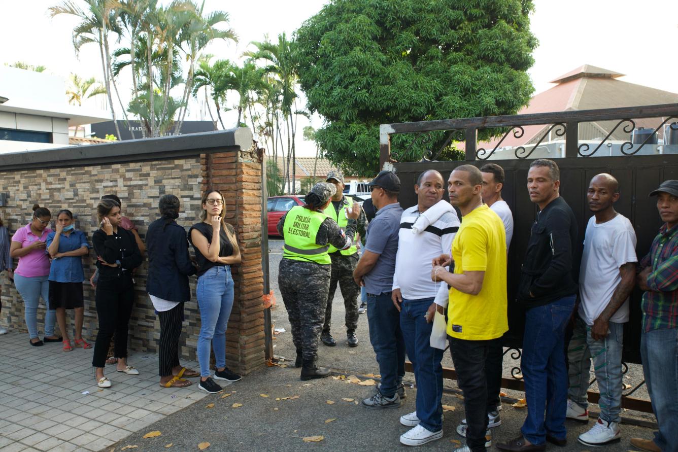 Votantes se encuentran en las afueras de un recinto electoral a la espera de ingresar, para ejercer su derecho al voto.