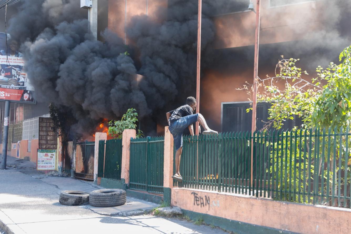 Un hombre intenta volar una verja para ingresar a un lugar en llamas.