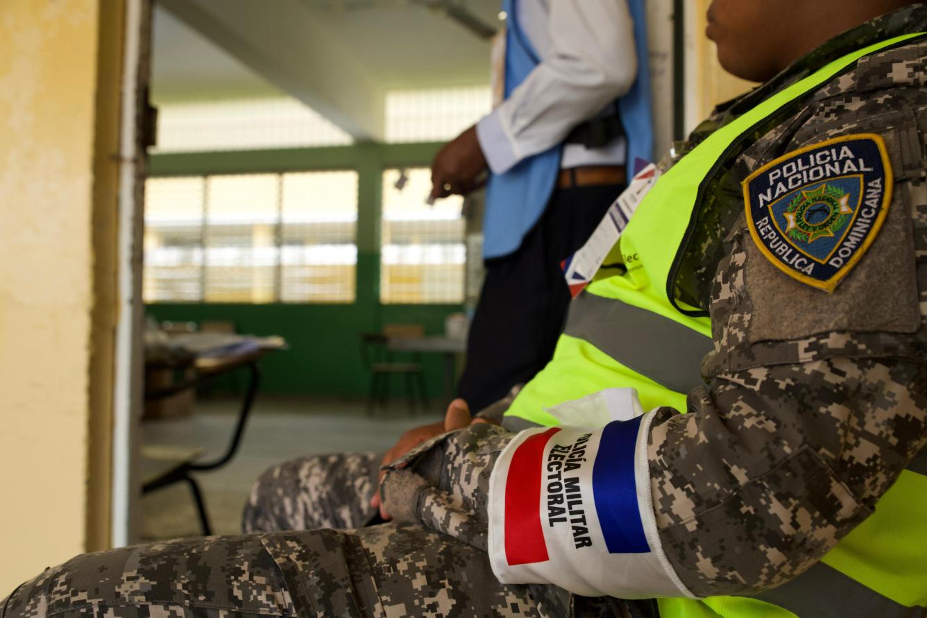 Fotografía muestra a miembro de la Policía Militar Electoral custodiando colegio electoral.