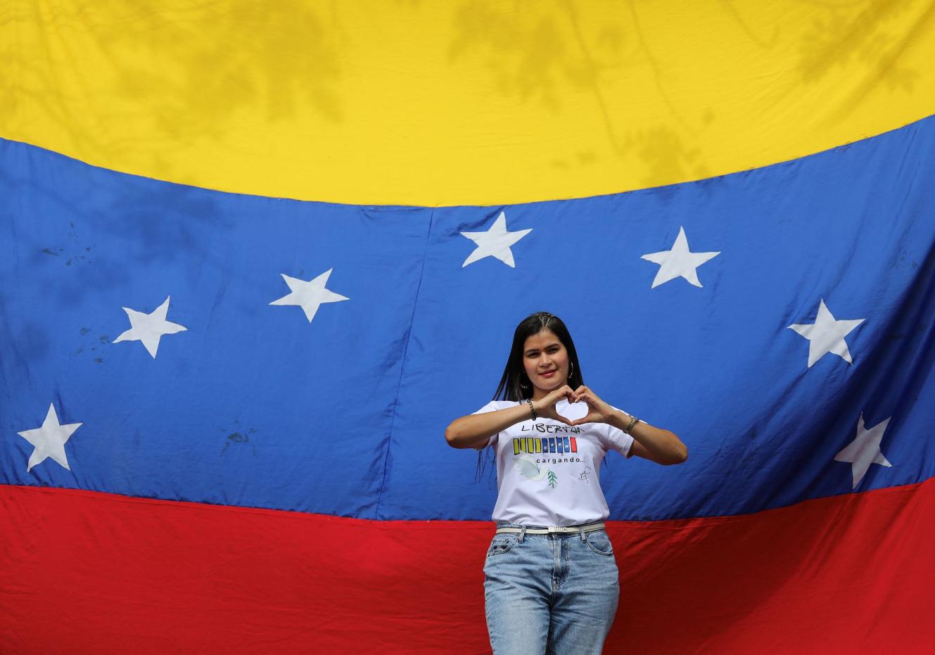Una mujer posa para una fotografía junto a una bandera venezolana frente al consulado de Venezuela en Medellín, Colombia, el 28 de julio de 2024.