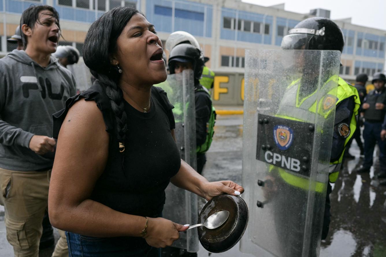 Opositores al gobierno del presidente venezolano Nicolás Maduro protestan con calderos frente a miembros de la Policía Nacional en el barrio de Catia en Caracas
