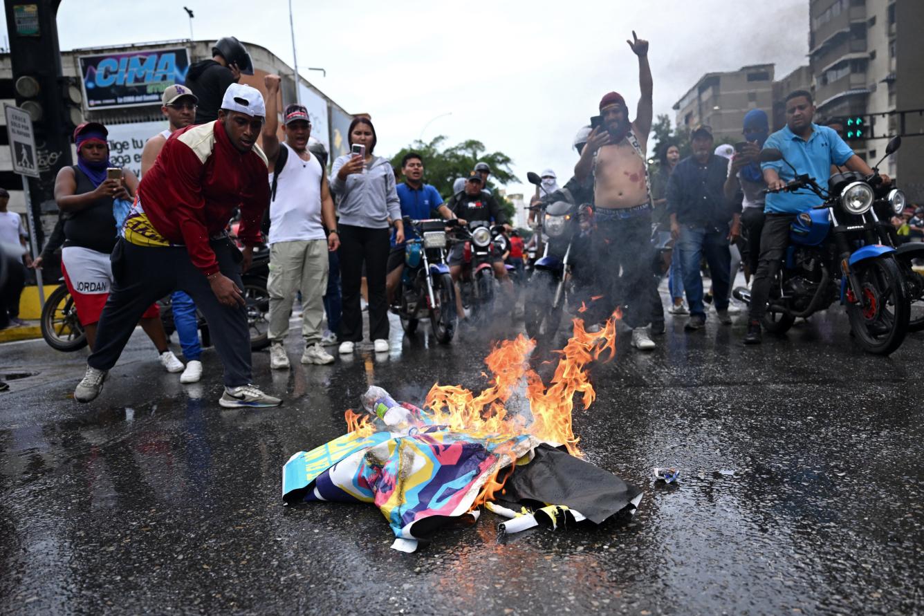 Opositores al gobierno del presidente venezolano Nicolás Maduro queman carteles de la campaña de Maduro durante una protesta en el barrio de Petare en Caracas, un día después de las elecciones presidenciales venezolanas.