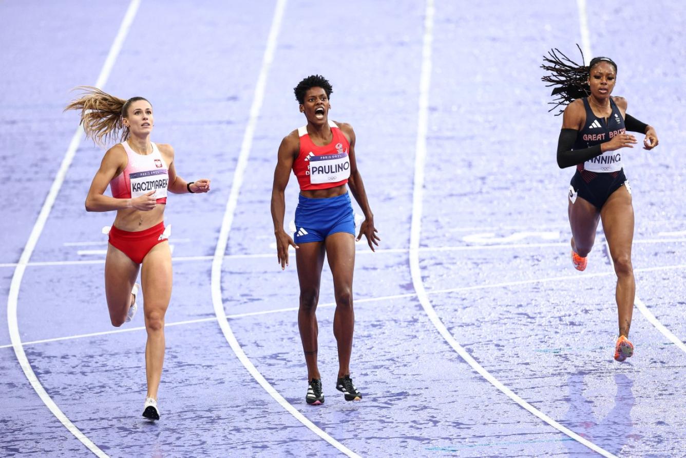 Dominican Republic's Marileidy Paulino (C) crosses the finish line ahead of Poland's Natalia Kaczmarek and Britain's Amber Anning in the women's 400m final of the athletics event at the Paris 2024 Olympic Games at Stade de France in Saint-Denis, north of Paris, on August 9, 2024. (Photo by Anne-Christine POUJOULAT / AFP)