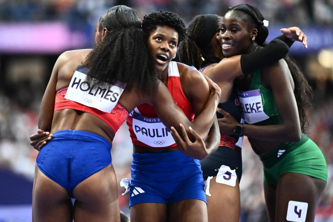 Dominican Republic's Marileidy Paulino celebrates with US' Alexis Holmes after winning the women's 400m final of the athletics event at the Paris 2024 Olympic Games at Stade de France in Saint-Denis, north of Paris, on August 9, 2024. (Photo by Jewel SAMAD / AFP)