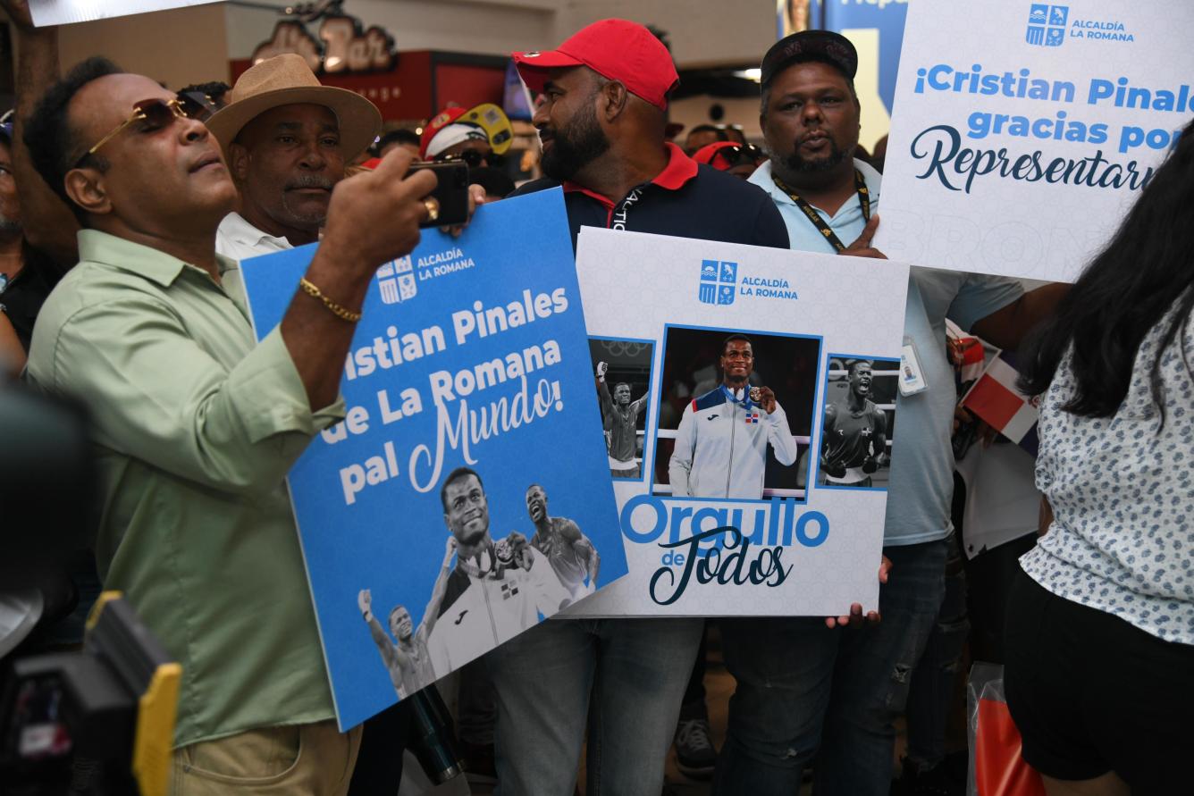 Con carteles con el nombre de Cristian Pinales, ganador de una medalla de bronce a su espera en el Aeropuerto Internacional de Las Américas (AILA)