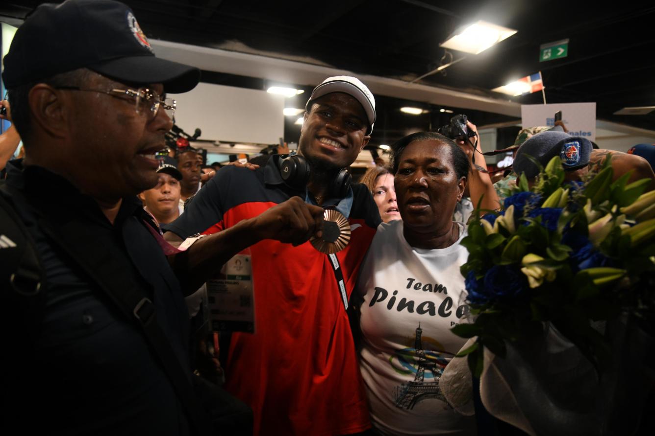 Cristian Pinales mostrando su medalla de bronce junto a su madre con un tshirt 