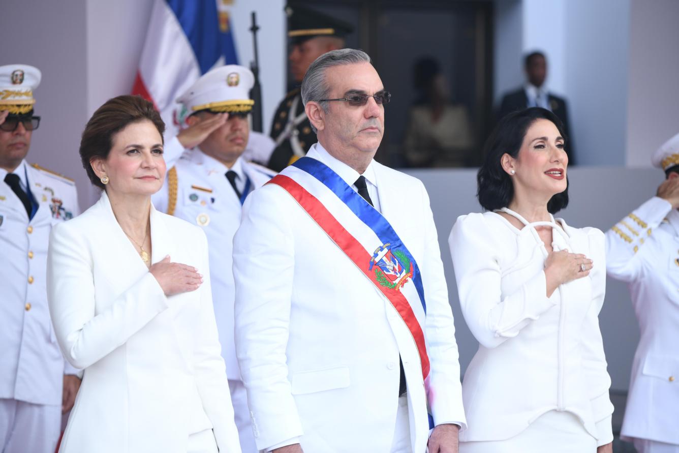 Abinader, Raquel Peña y Raquel Arbaje escuchan el himno nacional dominicano.