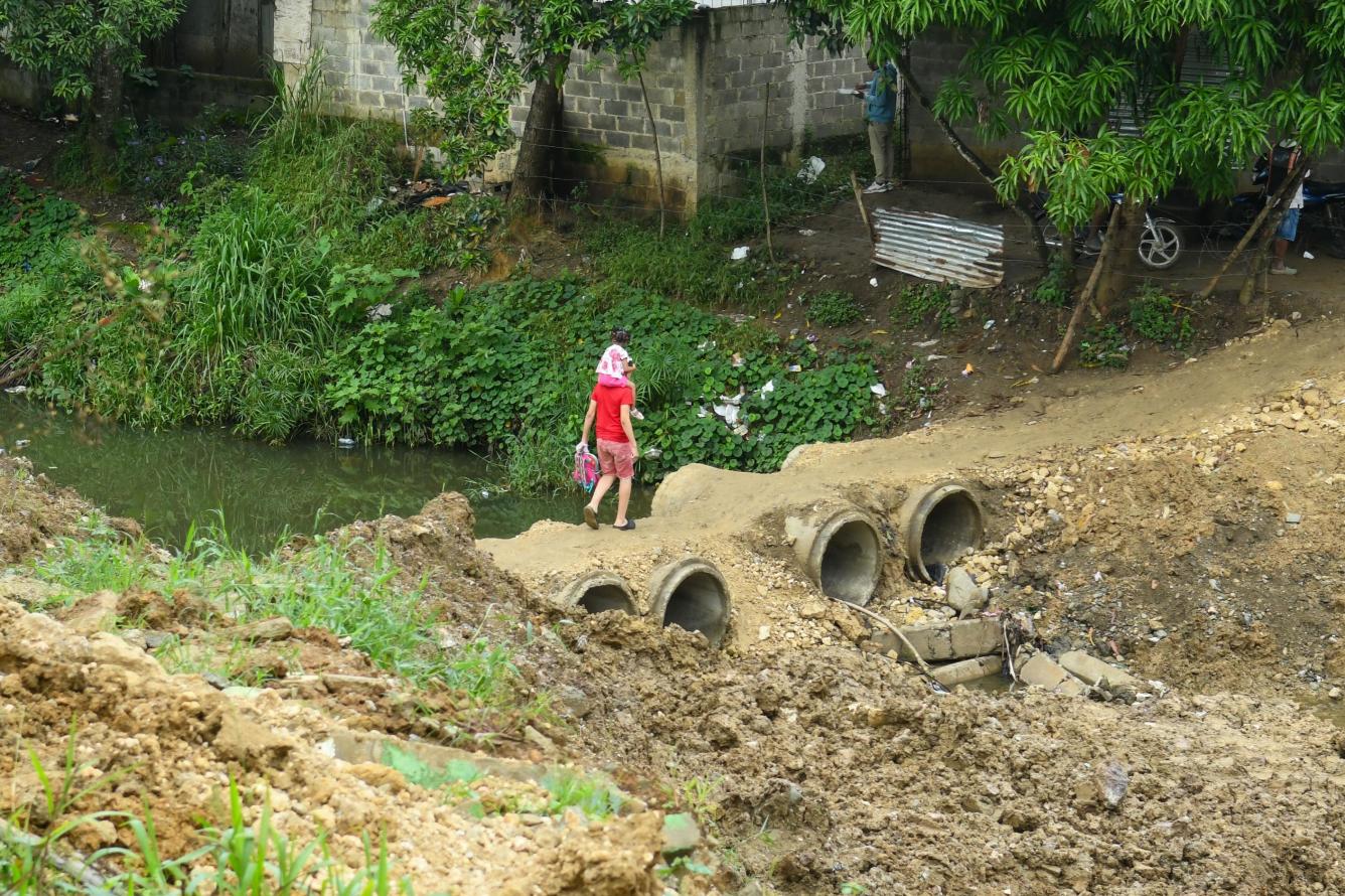 Joven carga niña en sus hombros en caminito al lado de construcción de puente en Pedro Brand