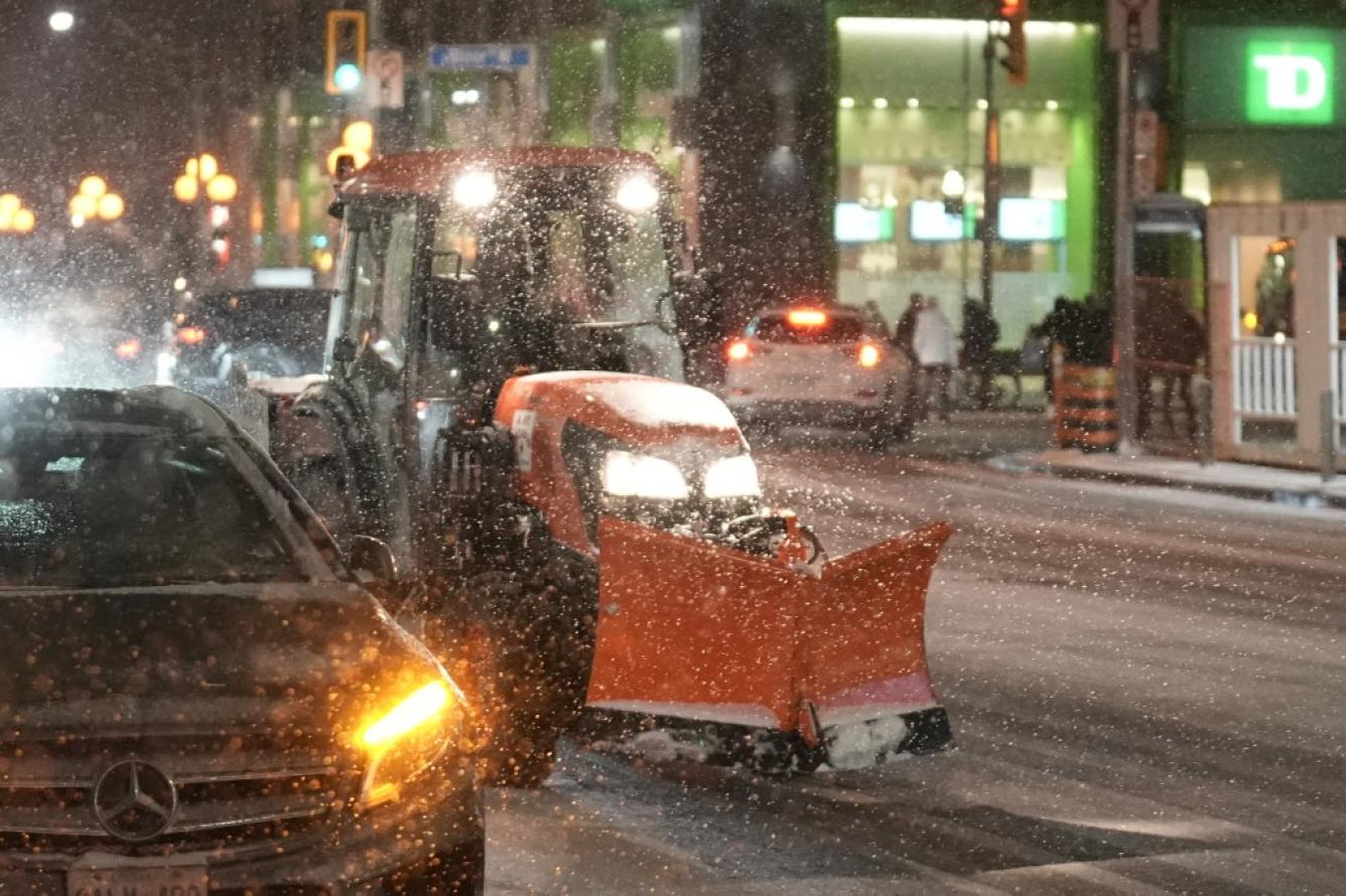 Un tractor con una parcela de nieve conduce durante una nevada en Toronto, Canadá.