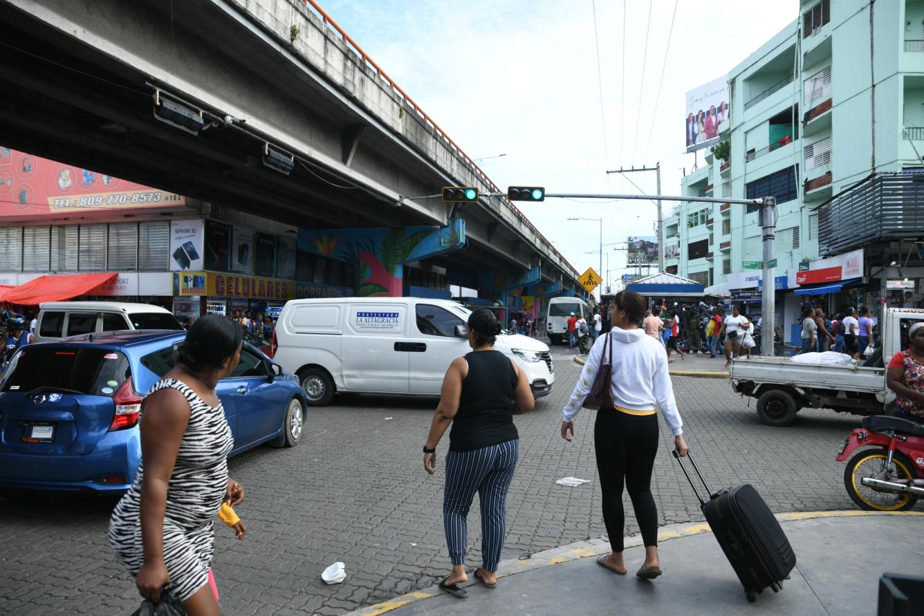 Joven camina hacia parada de autobuses con bulto y maleta