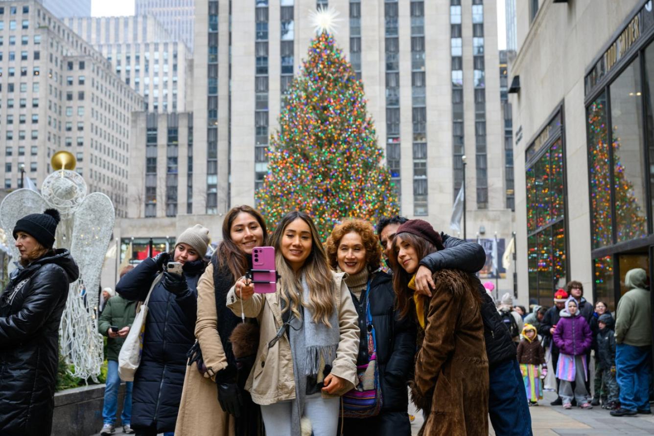 La gente usa un palo para selfies para tomar una foto con el árbol de Navidad de Rockfeller el día de Navidad el 25 de diciembre de 2024 en la ciudad de Nueva York.