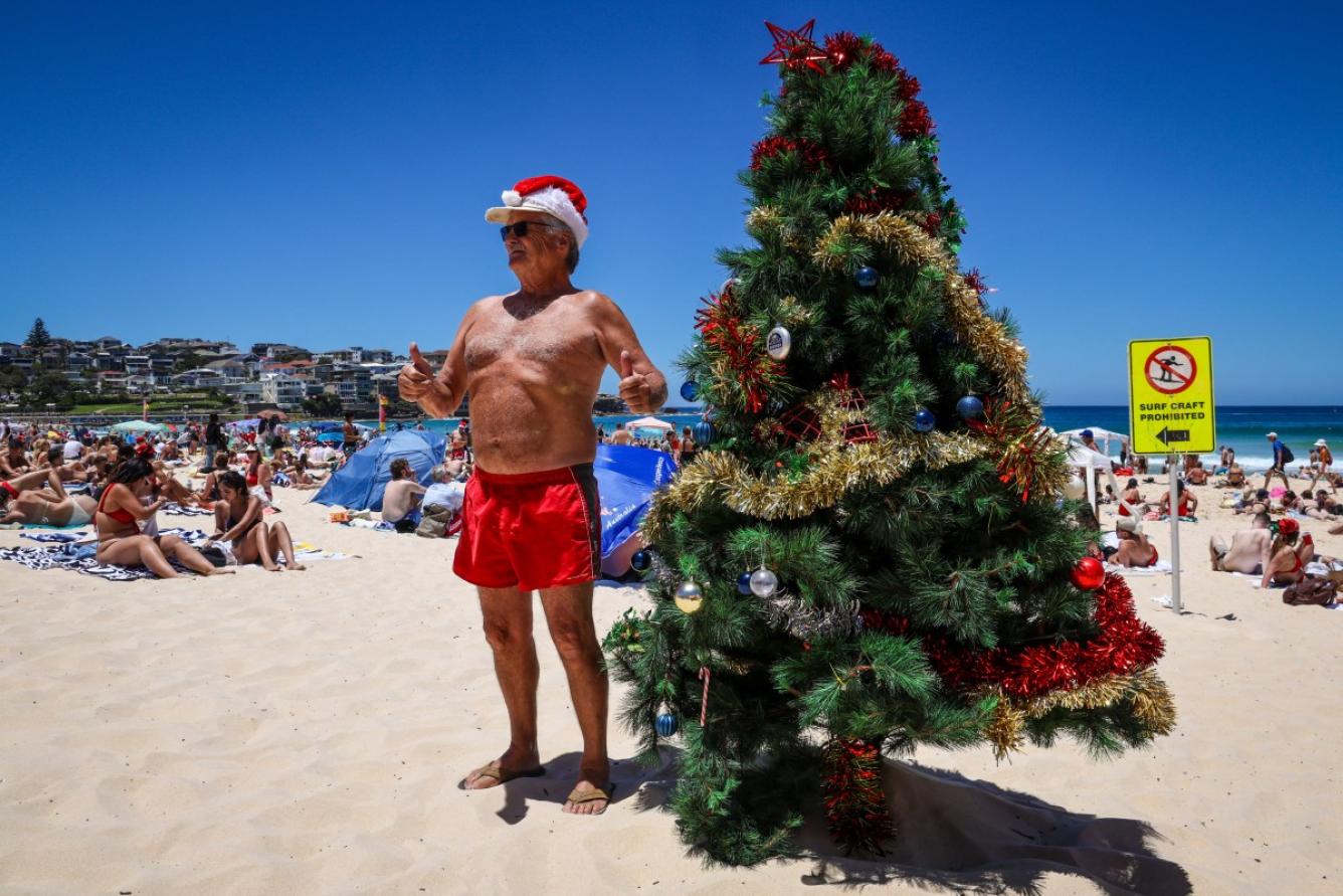 Un hombre con un sombrero de Navidad se encuentra junto a un árbol de Navidad en Bondi Beach el día de Navidad en Sydney, Australia el 25 de diciembre de 2024.