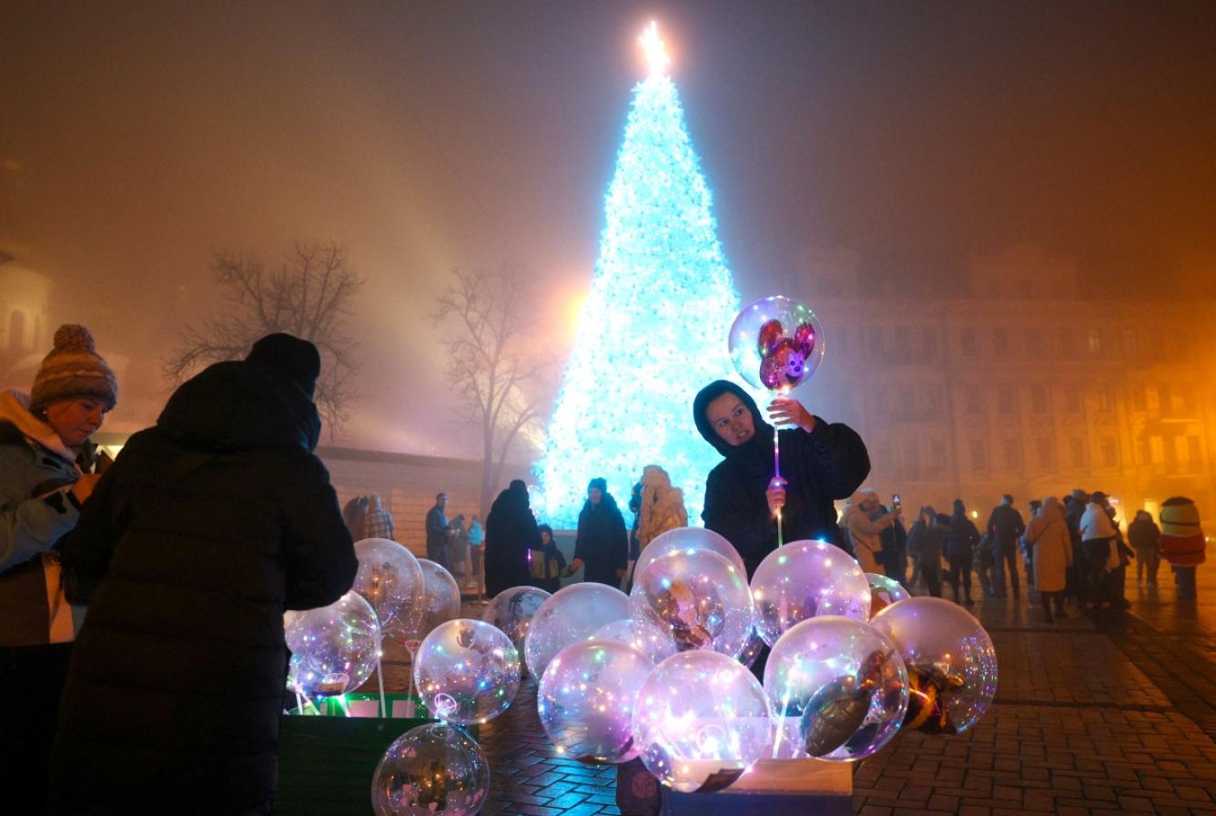 Una mujer compra un globo inflable cerca del árbol de Navidad en la Plaza Sofía en Kiev, el 24 de diciembre de 2024, en medio de la invasión rusa en Ucrania.