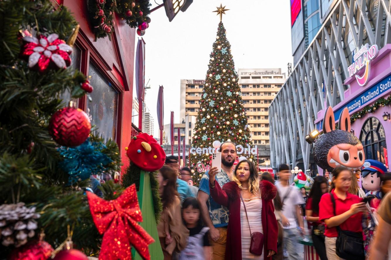 La gente se toma fotografías con un árbol de Navidad en la víspera de Navidad en el Central World Mall en Bangkok el 24 de diciembre de 2024.