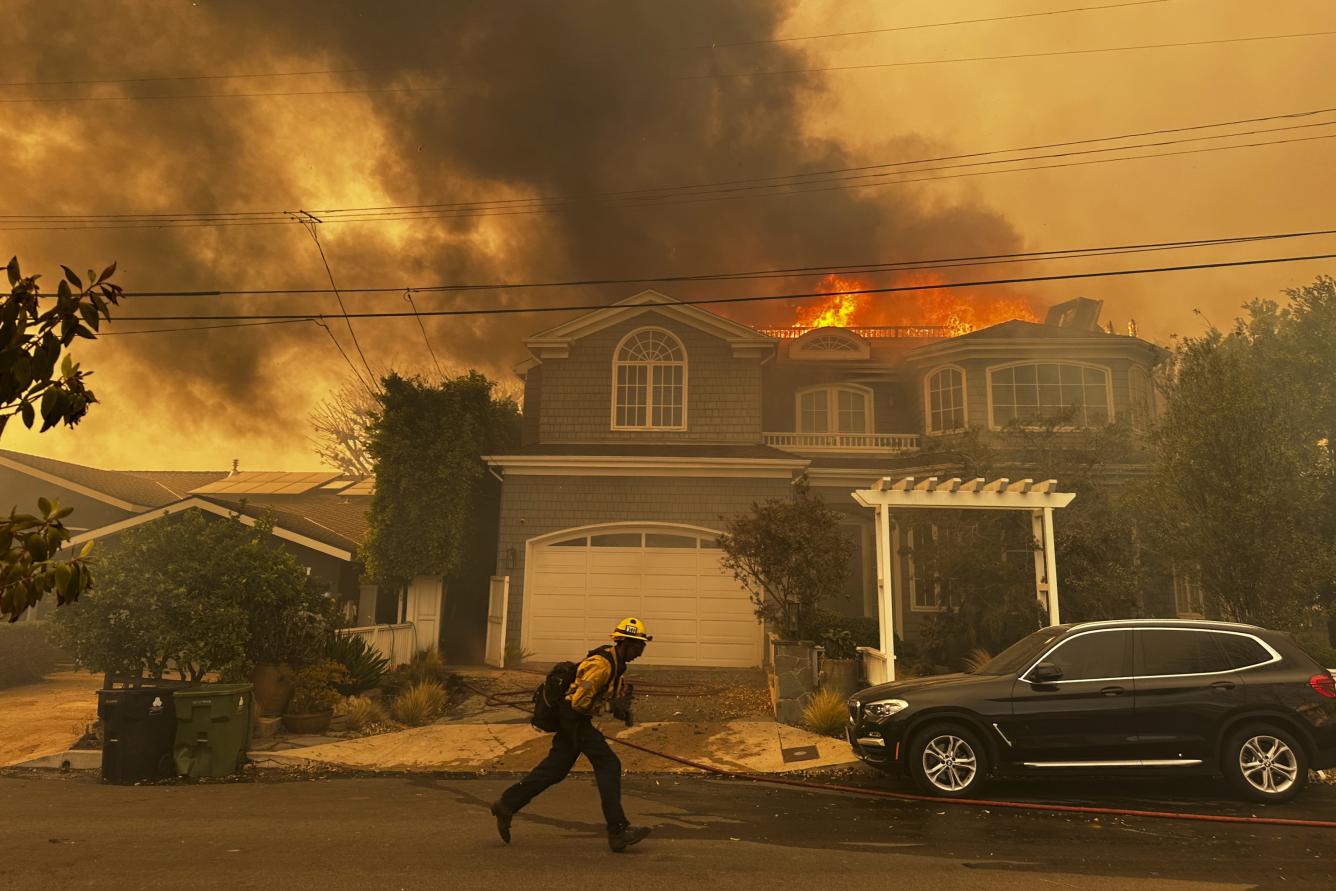 Una residencia arde mientras un bombero combate el incendio de Palisades