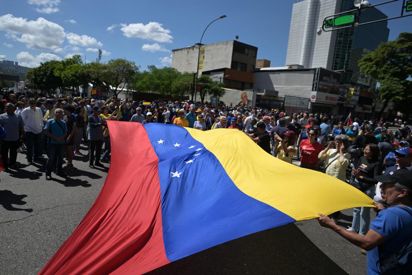 Los manifestantes despliegan una enorme bandera venezolana