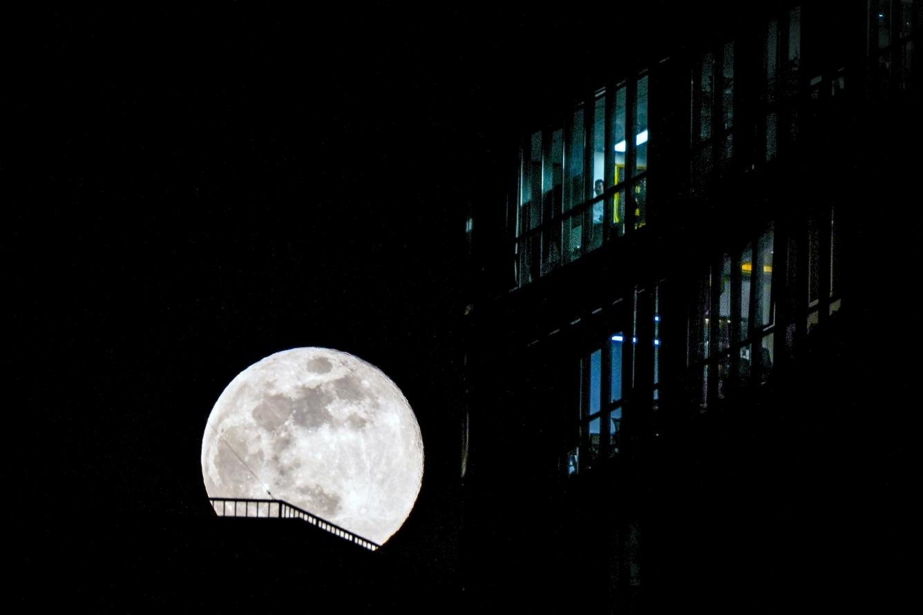 Un hombre se encuentra de pie cerca de una ventana mientras la primera luna llena del año