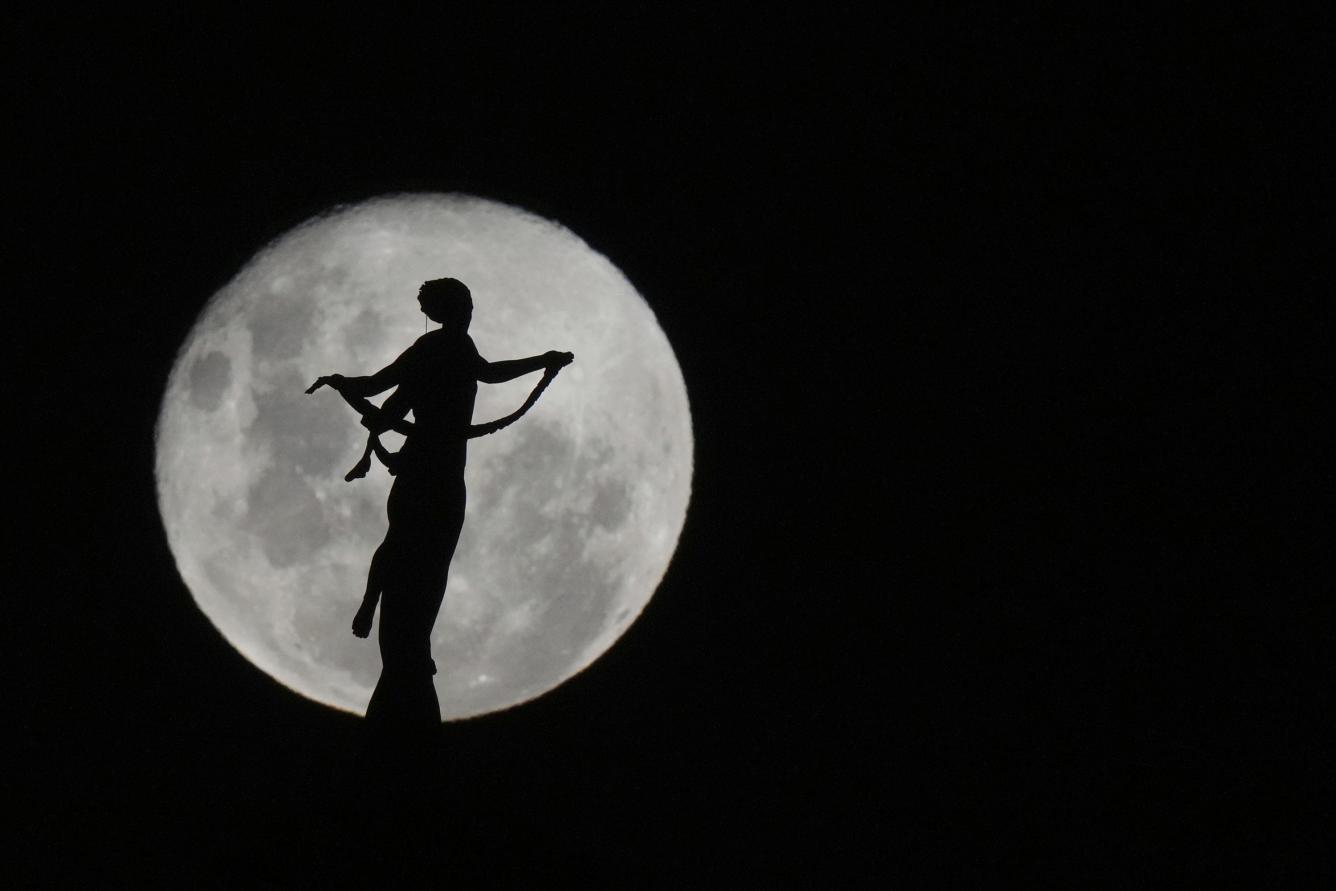 La luna con forma de lobo se alza detrás de la silueta de la estatua de la Paz Victoriosa