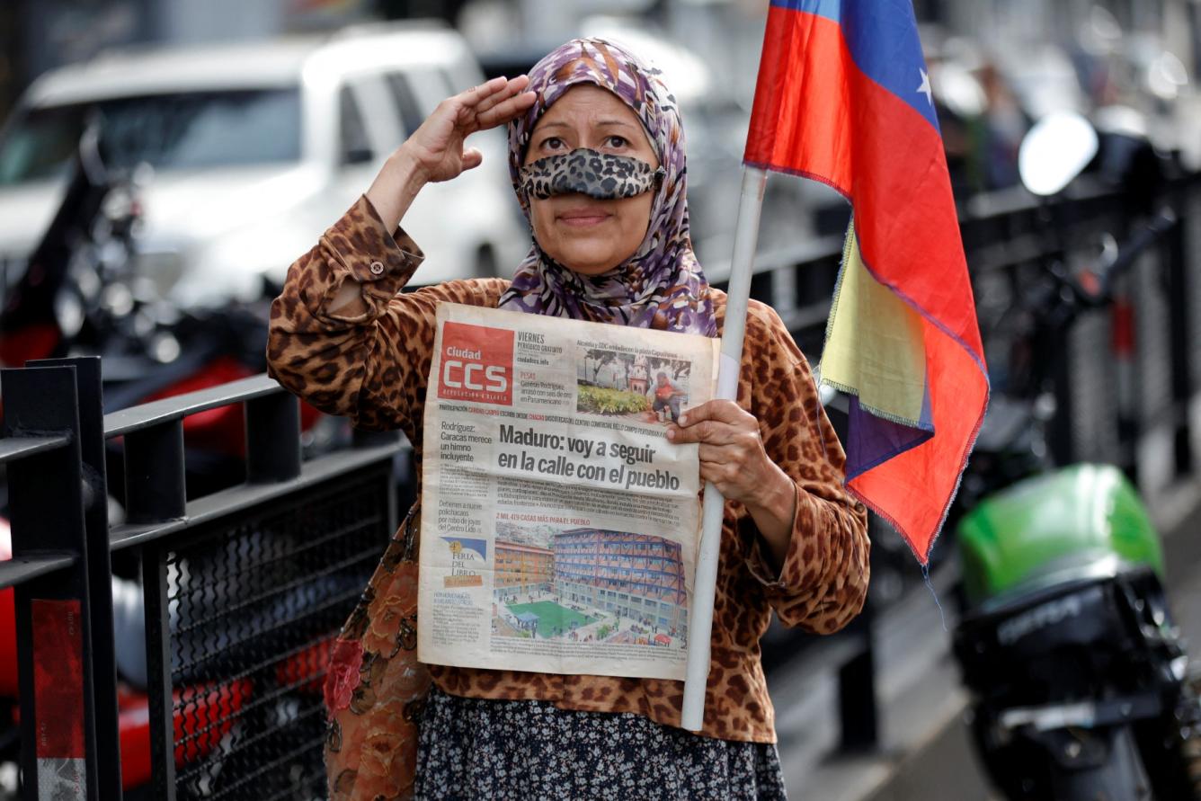 Una simpatizante del presidente venezolano, Nicolás Maduro, saluda mientras sostiene un periódico que dice 