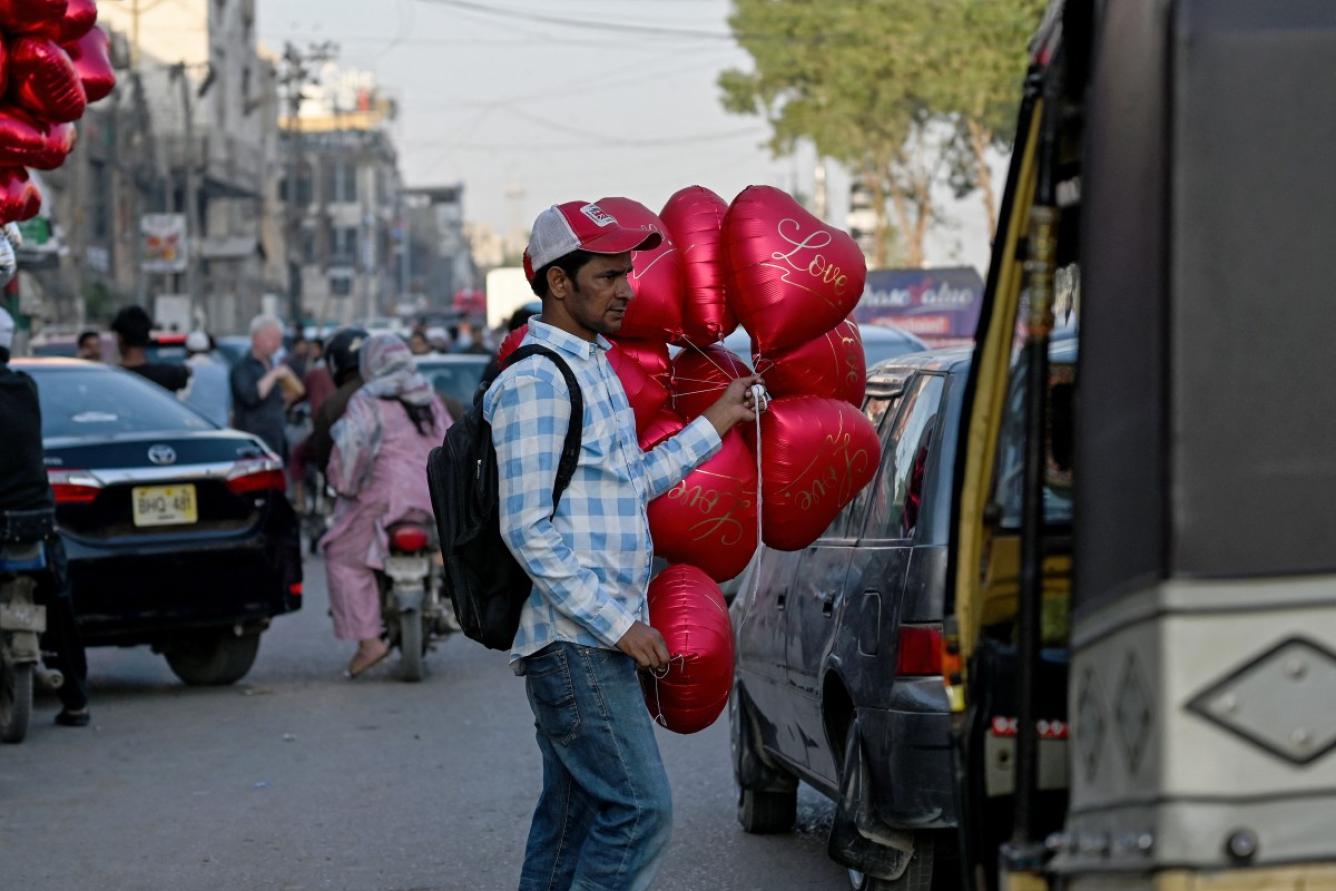 Un vendedor ambulante de globos con forma de corazón busca clientes en una calle el Día de San Valentín en Karachi, el 14 de febrero de 2026. (Foto de Rizwan TABASSUM / AFP)