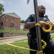 Un oficial de policía de Baltimore cuelga una cinta policial en el lugar de un tiroteo masivo en el vecindario de Brooklyn Homes el 2 de julio de 2023 en Baltimore, Maryland.