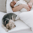 Una mujer y su bebé duermen junto a su mascota.