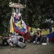 Migrantes sentados bajo un cartel que marca la frontera entre Panamá y Colombia.