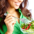 Primer plano de una chica comiendo ensalada de verduras frescas.