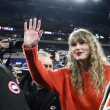 Taylor Swift saluda mientras camina con Ed Kelce