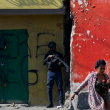 Una mujer pasa frente a un agente de policía armado que vigila una calle tras otra jornada de violencia de bandas en Puerto Príncipe, Haití, el 22 de marzo de 2024