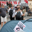 Turistas toman fotografías mientras manifestantes acampan en tiendas de campaña para protestar contra los desahucios y la crisis de la vivienda frente a la sede de la Presidencia, ayer en Madrid.
