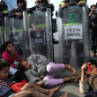 Acción. Niños migrantes descansan frente a una fila de policías mexicanos en uniformes de faena, cuando trataban de cruzar la frontera en Tijuana.