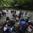 Migrantes, en su mayoría venezolanos, cruzan un río en la selva del Darién el 15 de octubre de 2022, en un recorrido de Colombia a Panamá, con la esperanza de seguir luego su viaje hacia Estados Unidos. La Agencia de la ONU para los Refugiados (ACNUR) y la Organización Internacional para las Migraciones (OIM) indicaron en un comunicado el jueves 13 de abril de 2023 que más 100.000 migrantes cruzaron esa ruta en los primeros meses del año y que, de seguir la tendencia, la cifra a final del año podría superar los 400.000. (AP Foto/Fernando Vergara, Archivo)