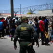 Un agente de la Patrulla Fronteriza camina a lo largo de una fila de migrantes que esperan entregarse a los agentes de la Patrulla Fronteriza de Aduanas y Protección Fronteriza de EE. UU. después de cruzar la frontera mexicana.