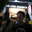 Delante de un mensaje proyectado en la fachada del consulado de España en Sao Paulo, un manifestante habla durante una protesta contra las expresiones racistas lanzadas a Vinícius Júnior, el martes 23 de mayo de 2023.