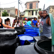 Comunitarios hacen filas para coger agua ante la escasez de la misma.