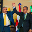 Leonel Fernández y Elías Wessin Chávez levantan sus manos tras la firma ayer de la alianza electoral de sus partidos, con miras a las elecciones de 2024.